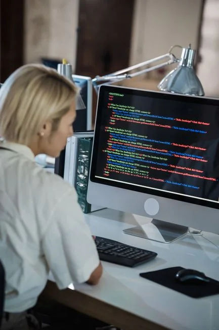 Woman using smartphone for online shopping with credit card in hand, festive background lighting.